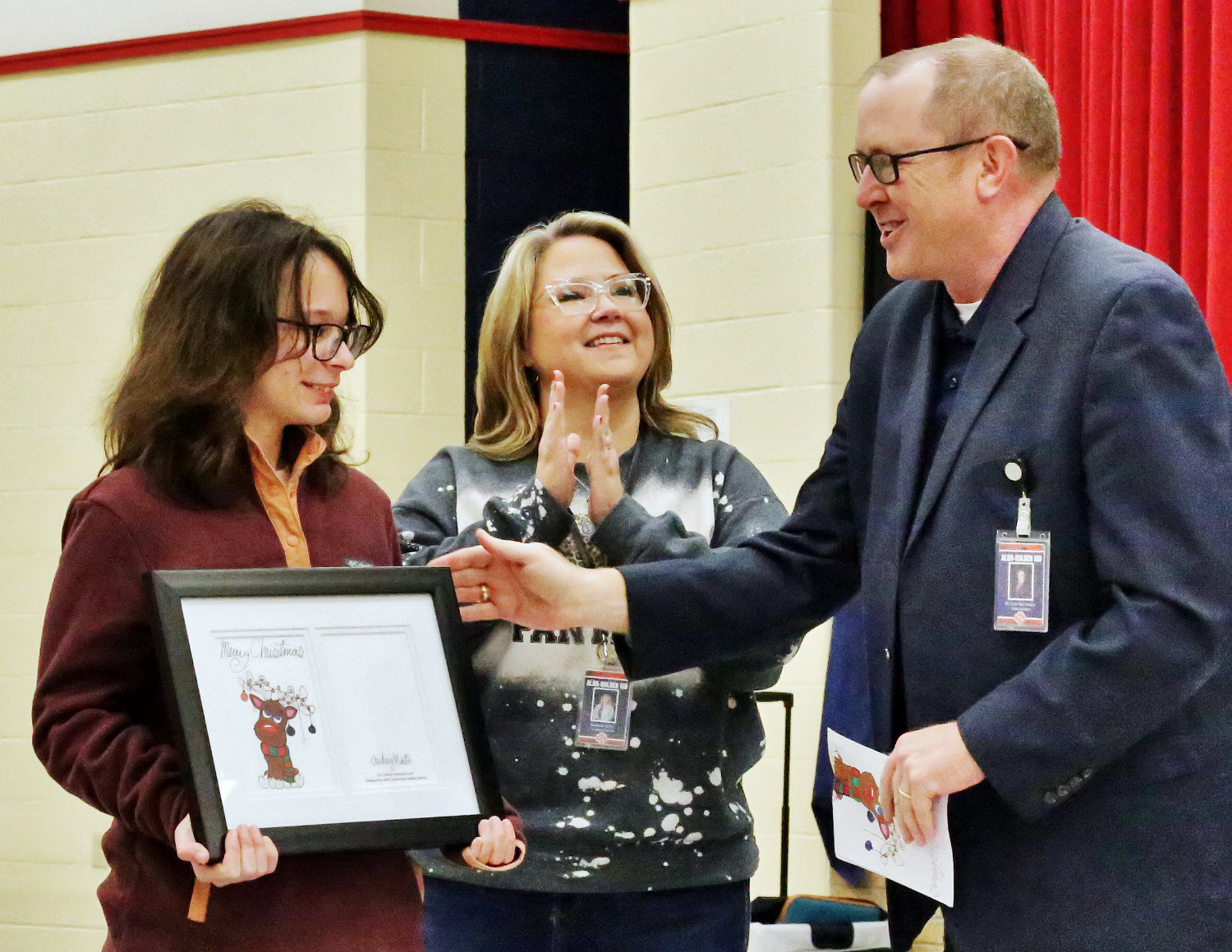 Audrey Martin, winner of the Alba-Golden schools 2021 Christmas card competition, receives an award from Superintendent Cole McClendon at Monday’s school board meeting. Pictured with Martin is art teacher Stephanie White.